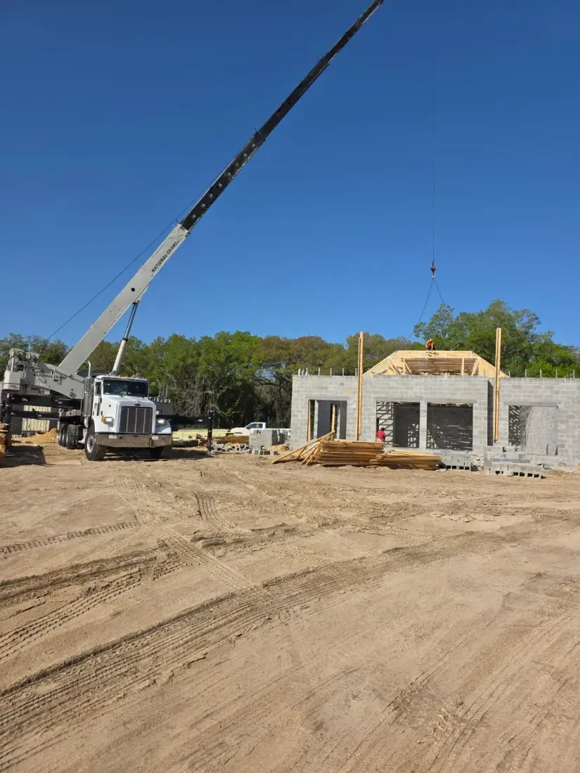 Crane lifting structural materials at the start of a framing project