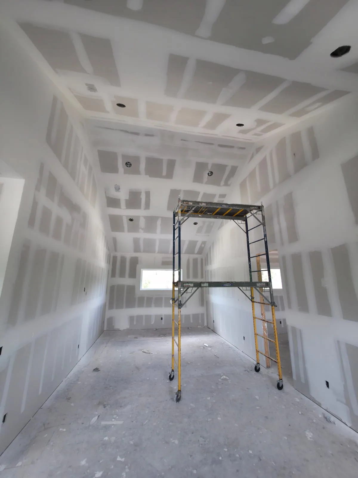 Drywall finishing and taping work in a high-ceiling residential interior in Central Florida