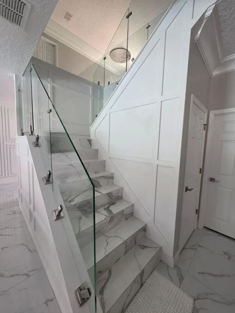Finished custom staircase with marble treads and glass railing