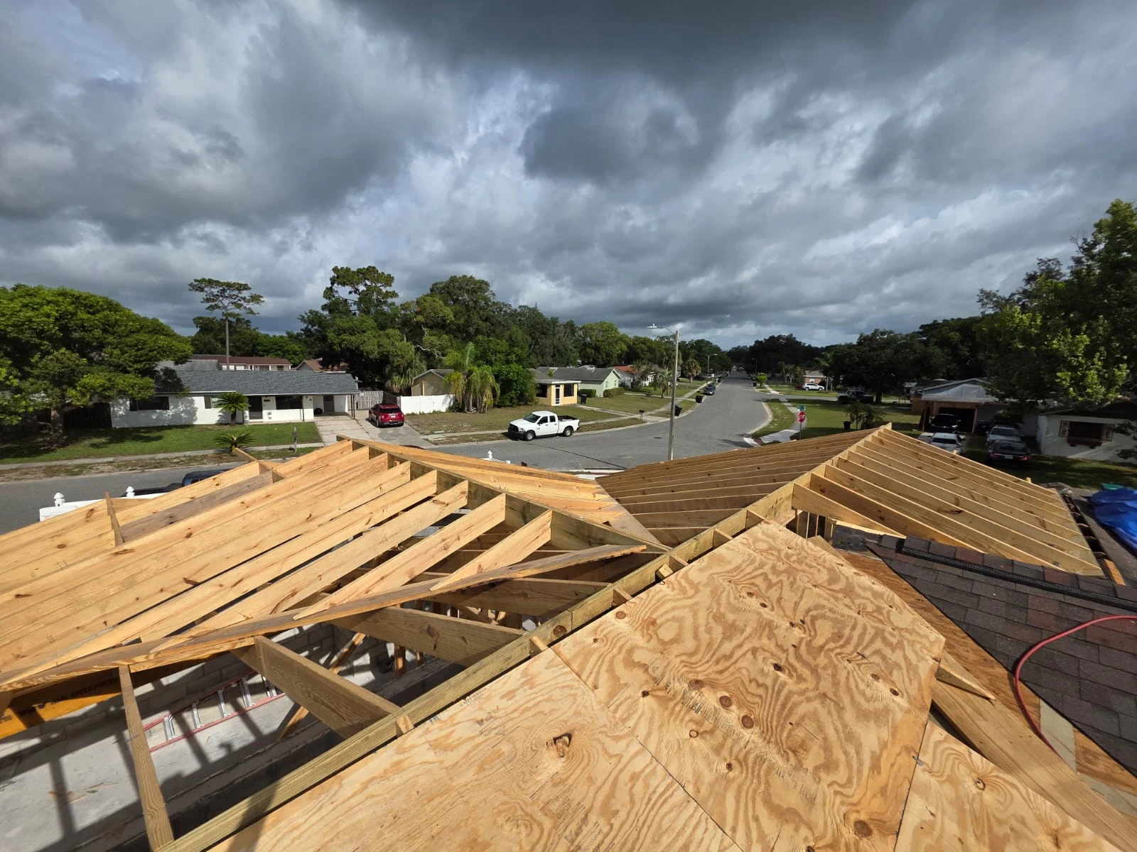 Aerial view of roof trusses and sheathing under construction, showing the roof framing structure